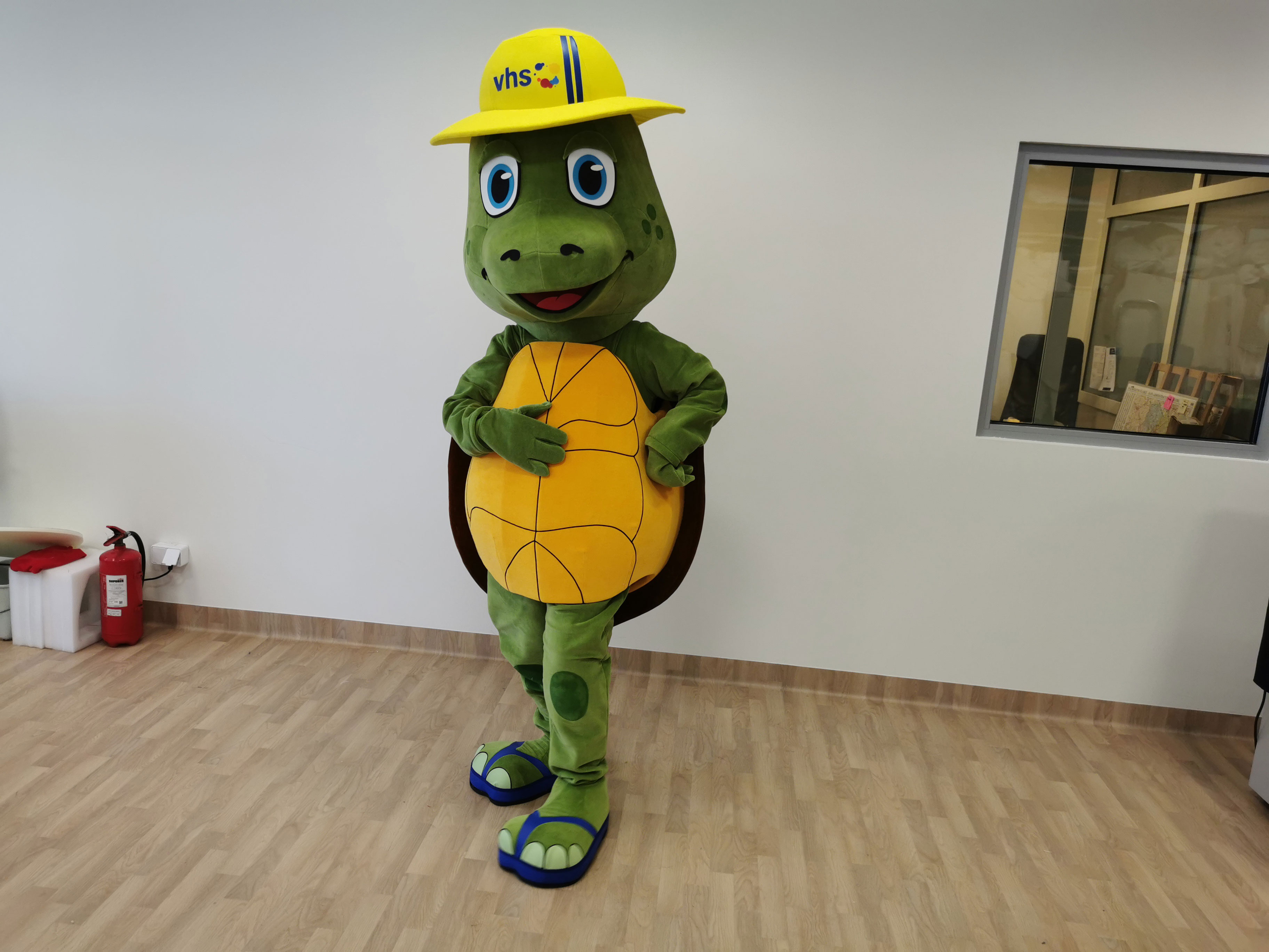Na fotografii widnieje strój reklamowy w postaci żółwia pozujący do zdjęcia w siedzibie firmy Elabika